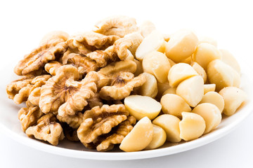 Some cashews, and macadamias on a white dish.