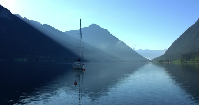 Establishing shot, Scenic view Clear water of Achensee lake, blue sky and boat reflecting lake.