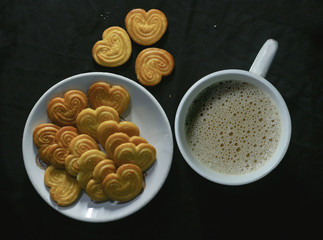 white cup of hot tea with biscuit love shape