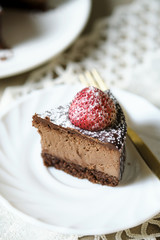 Mousse chocolate cake with strawberry and icing powder sugar. set on cafe table.