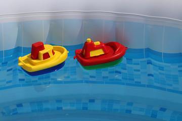 Bright colored toy boats float in the home pool
