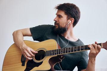 Obraz premium man holding a guitar performing learning music dark t-shirt light background