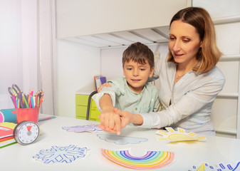 Child with autism spectrum disorder learn weather using cards, teacher hold hands and point to...