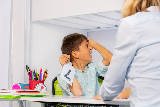Boy with autism spectrum disorder show pain and negative expression while learning numbers sitting by teacher