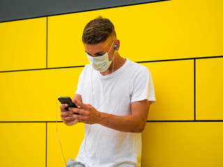 Caucasian male using his phone on yellow wall background