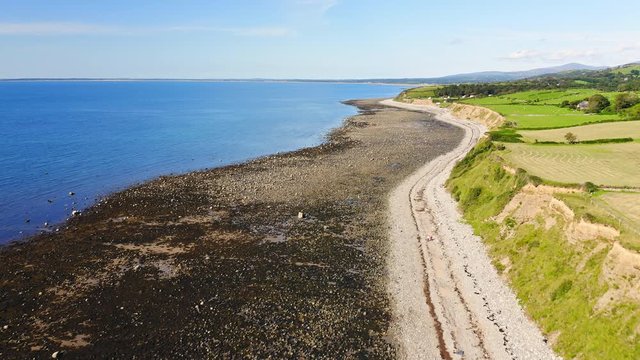 Bright Blue Sea Sea At The Village Of Trefor With Lush Field And Rough Coast In Llyn Peninsula, Wales, UK - dolly drone shot