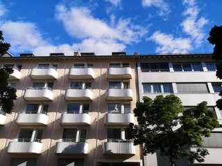 Wohnhaus mit geschwungenen Balkons vor blauem Himmel mit weißen Wolken im Sommer im Westend von...
