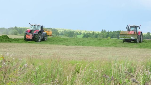 Two Tractors collecting silos aon field Close up
