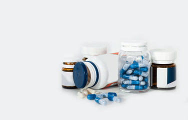 Blue pills in glass and plastic bottles on white background, health care concept.