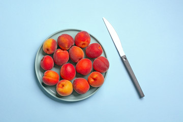 pile of ripe apricots in plate with knife beside - closeup