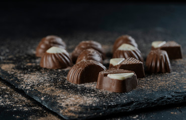 chocolate bonbons on black background with cocoa powder