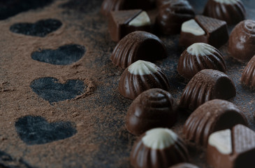 chocolates on black stone with cocoa powder forming hearts