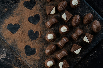 chocolates on black stone with cocoa powder forming hearts