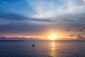Sunset landscape with sailboat sailing on the sea.