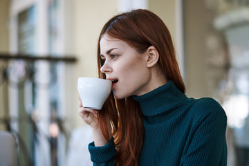 Red-haired woman on a street cafe with a cup of coffee relaxing