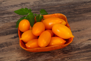 Yellow tomato heap in the wooden bowl