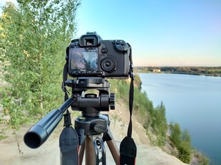 Saint Petersburg, Russia, August 8, 2020: Canon camera on tripod captures the sunset by the lake. 