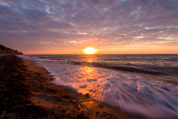 Fototapeta na wymiar Beautiful sunrise at the sea on a cloudy morning. Sandy shore with seaweed. Black sea. Sanzhiika. Ukraine