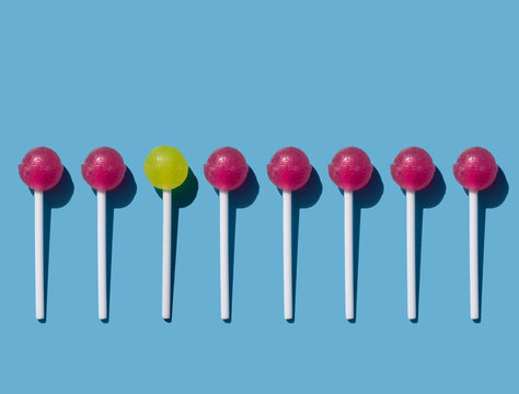 caramel on a stick on a blue background, chupa chups pattern, red and yellow lollipop