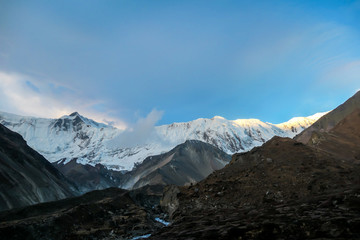 A close up view on high, snow capped Himalayan peaks along Annapurna Circuit in Nepal. Barren and sharp slopes. Mountains are partially shrouded with clouds. Exploration and discovering new places