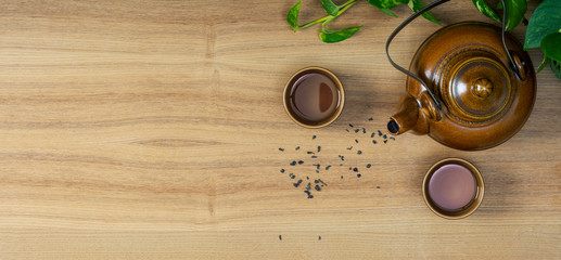 Asian tea set and tea leaves on a wooden table.