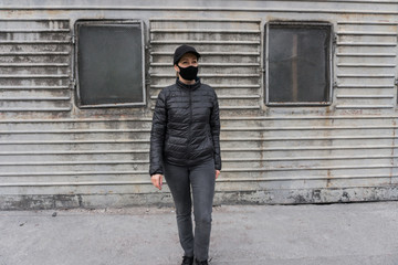 Woman wear protective face mask against influenza virus. Black mask on the dark industrial zone background. Pandemic coronavirus 2020 and Quarantine. Stop the virus, infection and epidemic diseases.