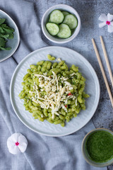 Recipe for durum wheat pasta with cheese, pesto and arugula on a gray background. Healthy vegetarian lunch without meat. Balanced proper nutrition for weight loss and diet.