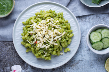 Recipe for durum wheat pasta with cheese, pesto and arugula on a gray background. Healthy vegetarian lunch without meat. Balanced proper nutrition for weight loss and diet.