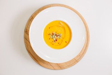 a plate of pumpkin soup garnished with pumpkin seeds. view from above
