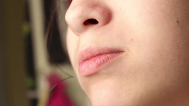 A teenage girl eats chips, chewing carefully. Part of the face. Close up.