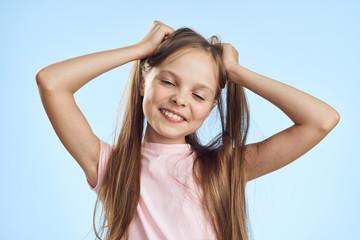 Girl holding hair smile pink t-shirt blue background childhood emotions