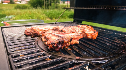 Home barbecue with charcoal in the backyard grilling steaks and other meats for carnivore diet.