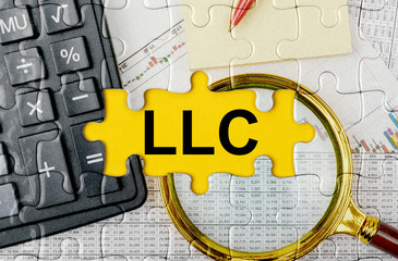 Puzzle with a calculator, magnifying glasses and financial documents in the center inscription -LLC