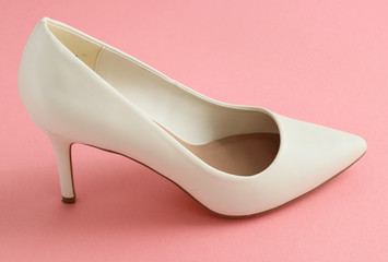 White high heel shoes
One of white high-heeled shoes stands on a pink background, close-up side view.