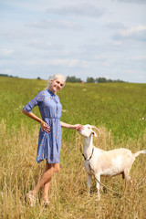 Portrait of a young girl with a goat in a wheat fieldess