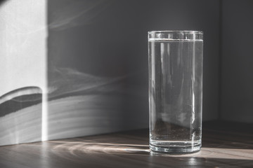 full glass of crystal clear water in the morning sun. a glass of water in the morning. healthy eating, health care
