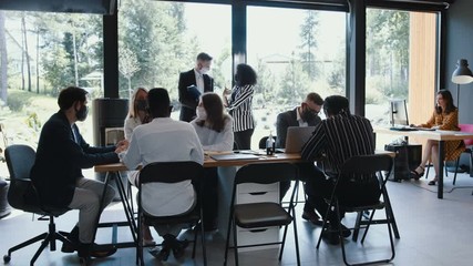 Business meeting with safety measures against COVID-19. Multiethnic team working at office table at modern light office. - Powered by Adobe