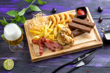 Beer snack. Garlic croutons, onion rings, chicken wings, grilled sausages, smoked cheese, ketchup, french fries.