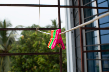 Fototapeta na wymiar A trio of colourful plastic clothes pegs hanging on a washing line with blurred background