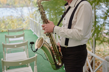 Saxophonist in white jacket plays the saxophone. Saxophonist jazz man with saxophone on wedding...