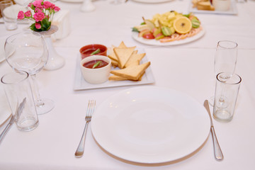 Table set with sparkling wineglasses, plates with serviette and cutlery on table, copy space. Place setting at wedding reception. Table served for wedding banquet in restaurant