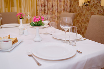 Table set with sparkling wineglasses, plates with serviette and cutlery on table, copy space. Place setting at wedding reception. Table served for wedding banquet in restaurant