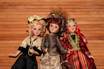 Three dolls in chic outfits on a wooden background.