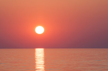 Zbliżenie na zachód słońca nad spokojną taflą morza - prosta linia horyzontu - wyraźne kolory