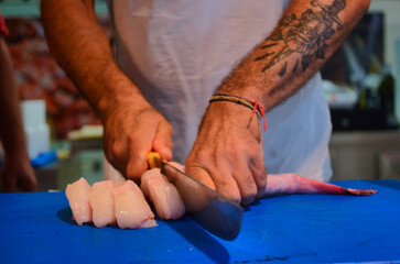 hands of a man cutting and cleaning a fresh fish in chunks