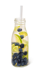 Cold fresh detox beverage of blueberry and lime with water in glass bottle, isolated on white background.
