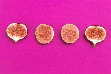 Four halves of figs on pink background.