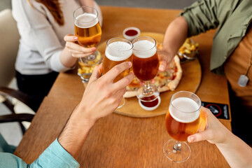 Close-up of friends toasting with beer in a cafe.