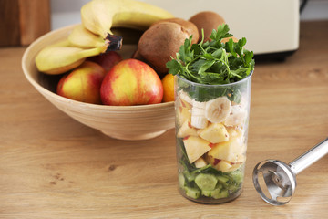 Glass of delicious yogurt with mint and fresh strawberries, banana, lime, nectarine in a wicker basket on a wooden table