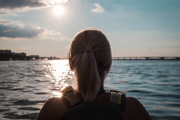 Close up of young woman kayaking on the river at sunset in sunny summer day
